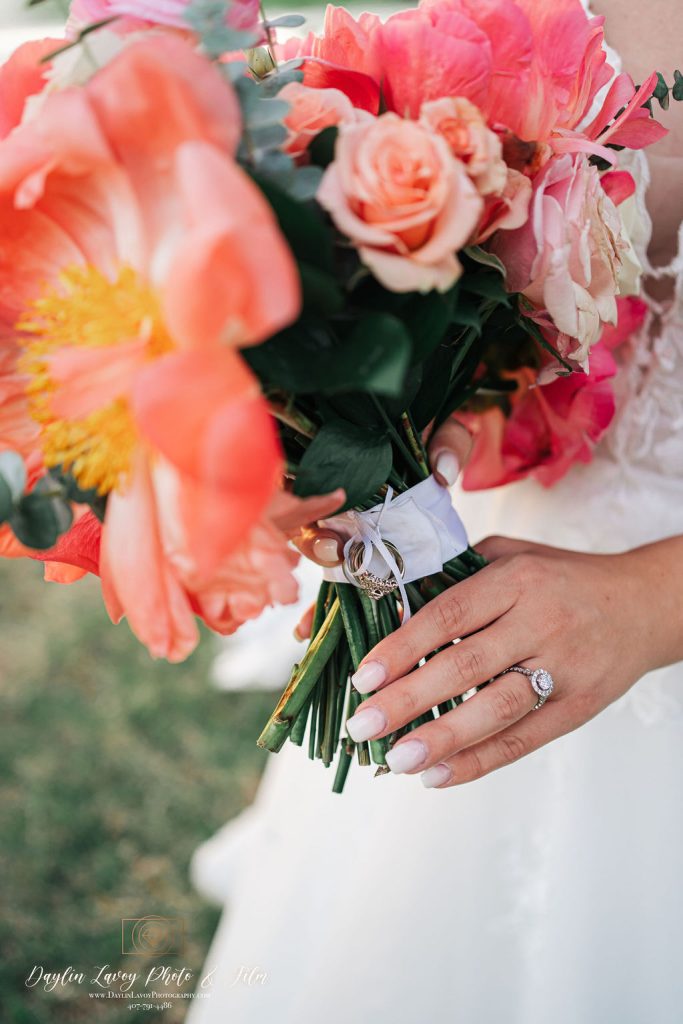 Bride holding a bouquet of bright coral and pink flowers.